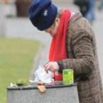 A woman looks through garbage in Warsaw Poland