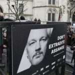 Stella Assange wife of Julian speaks besides a poster of J Assange at the Royal Courts of Justice in London
