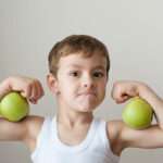 boy with green apples showing biceps face