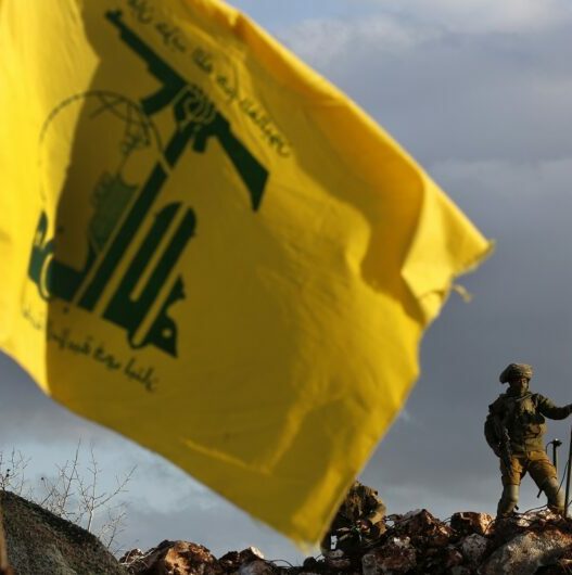 lebanon tense border israeli soldier sets up cameras at their new position in front of a hezbollah flag 768x530 1